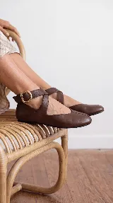 Chatitas de cuero color chocolate, con diseño de tiras cruzadas en el empeine y tira ajustable al tobillo con hebilla metálica dorada.