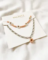 Set de dos collares: uno corto de cuentas color salmón con flores blancas y centro dorado, y otro más largo de cadena plateada con dije de flor de cuentas color salmón.