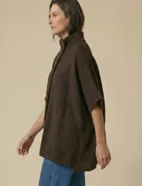 Capa tejida color fucsia, con cuello alto abotonado y mangas cortas estilo japonesa. Tejido de punto grueso.