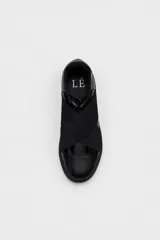 Zapatillas urbanas de mujer color negro, con bandas elásticas cruzadas sobre el empeine, detalles en charol y diseño slip-on.