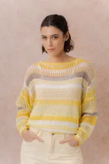 Buzo tejido de punto calado con rayas horizontales multicolor en tonos azul, amarillo, celeste y blanco, con escote bote, mangas largas y hombros caídos. Incluye top básico al tono.