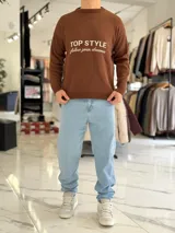 Sweater de punto color beige con cuello redondo, manga larga y diseño estampado en el pecho con las frases "TOP STYLE" y "follow your dreams" en color marrón.