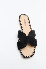 Sandalia baja con capellada de tiras cruzadas trenzadas en color negro. Presenta una plantilla con borde decorado con costuras en zigzag y suela plana.