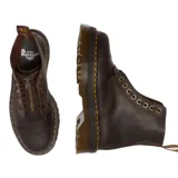 Botas de plataforma Dr. Martens modelo Sinclair, confeccionadas en cuero Crazy Horse de aspecto desgastado. Presentan un diseño con cierre frontal extraíble, cordones, suela estriada Quad y costuras amarillas características de la marca.