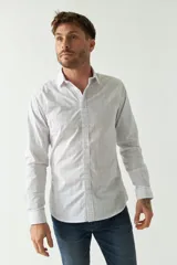 Camisa de hombre de corte slim fit, confeccionada en algodón con diseño de rayas verticales finas en tonos claros. Presenta cuello clásico, cierre frontal con botones y logo bordado en el pecho.