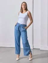Pantalón celeste de lyocell, corte ancho, con pretina elastizada con lazo de ajuste, bolsillos verticales y ruedo desflecado.