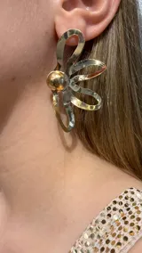 Caravana de diseño floral con pétalos calados de metal dorado y centro esférico pulido.