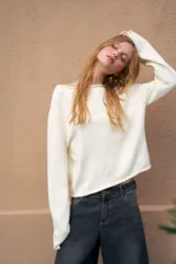 Sweater de tejido de punto color marrón, crop, con mangas largas y cuello redondo. Presenta un pequeño bordado rojo en el pecho y en el borde inferior.