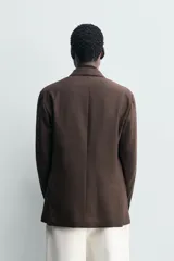 Blazer de corte regular fit confeccionado en tejido de lana, con cuello de solapas de muesca, manga larga con puños abotonados, bolsillos de vivo en el pecho y de plastrón en la cadera, cierre frontal de un botón y aberturas en la espalda.