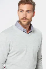 Suéter de tejido fino color azul marino, con cuello en V y manga larga. Presenta un pequeño logo bordado en el pecho.