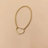 Pulsera de malla metálica con dije central en forma de corazón, ambos en acabado dorado.