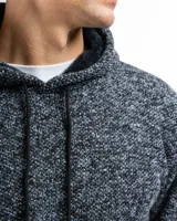 Buzo con capucha tejido en punto, color gris jaspeado, con bolsillo frontal tipo canguro, cordones ajustables con punteras metálicas y terminaciones en rib en puños y ruedo.