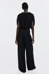 Body colaless negro con diseño drapeado y top de malla superpuesto de mangas cortas y escote redondo.
