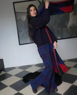 Pantalón de lana a cuadros azul, verde y rojo, entallado hasta la rodilla y con caída amplia tipo oxford, tajos laterales, elástico en la cintura y cierre oculto.