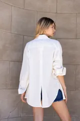 Camisa de lino color crudo, de manga larga y calce holgado. Presenta canesú y cartera con botones personalizados en la espalda.