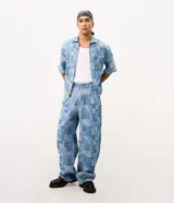 Pantalón de jean de algodón con diseño jacquard geométrico, de corte super baggy, tiro medio, bolsillos funcionales y cierre frontal con botón y cremallera.