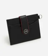 Billetera compacta Satinato de poliuretano color negro, con solapa frontal con botón a presión, detalles en rojo y argolla lateral metálica.