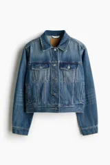 Campera de denim de algodón rígido, color azul, con cuello clásico y cierre frontal de botones metálicos. Cuenta con bolsillos superiores con solapa y botón, bolsillos laterales insertados y puños abotonados.