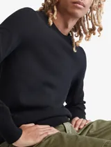 Sweater negro de lana merino de cuello redondo y corte clásico. Tiene puños y dobladillo con punto canalé.