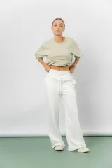 Pantalón blanco de silueta amplia y caída fluida, con cintura alta elastizada y lazo regulable con terminaciones metálicas.