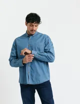 Camisa de jean de manga larga con cuello clásico, cierre frontal con botones y bolsillo tipo parche en el pecho.