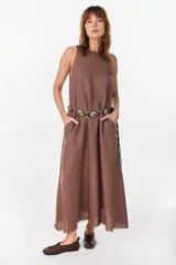 Vestido midi verde de lino italiano, con diseño sin mangas, cuello redondo y estampado de líneas onduladas punteadas. Cuenta con bolsillos laterales.