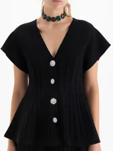 Cardigan de tejido de punto con textura acanalada, color negro, de manga corta y corte entallado. Presenta un escote en V y cierre frontal con botones decorativos de pedrería.