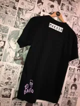 Remera negra de algodón con estampa amarilla y blanca con la frase "Eat my shorts" y la boca de Bart Simpson.