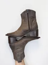 Bota de caÃ±a baja estilo texano confeccionada en cuero 100% genuino en tono marrÃ³n taupe, con taco cuadrado y cierre lateral.