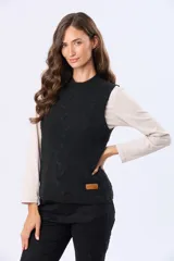 Chaleco tejido color negro, con cuello alto y diseño de trenzas en el frente. Tiene un parche de cuero sintético marrón con logo en el dobladillo inferior.