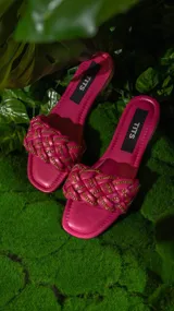 Sandalias negras con tiras trenzadas y cadena dorada.