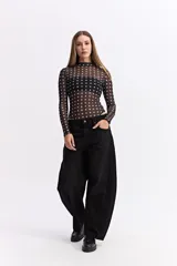 Body de manga larga confeccionado en tejido mesh transparente con estampado de lunares blancos sobre fondo negro. Presenta cuello alto y un diseño ajustado al cuerpo.