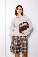 Camisa blanca de broderie con cuello alto, cuerpo y puños con frunces elásticos, y mangas largas abullonadas.