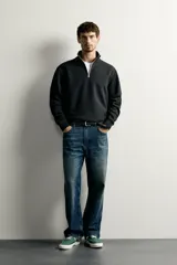 Sudadera negra de corte regular fit, con cuello subido, cierre frontal de cremallera corta y acabados en rib elástico en puños y cintura.