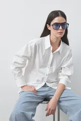 Camisa de manga larga de algodón en color blanco, con cuello clásico, cierre frontal de botones y silueta relajada.