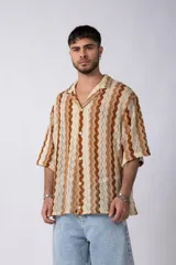 Camisa de manga corta con cuello solapa, confeccionada en tejido de punto crochet con patrón ondulado en tonos marrón y beige.