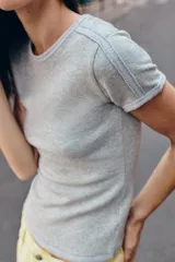 Camiseta de manga corta gris melange con cuello redondo y costuras decorativas visibles en los hombros.