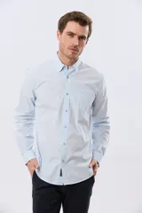 Camisa celeste de manga larga confeccionada en algodón, con cuello camisero, cierre frontal de botones, bolsillo en el pecho y diseño de cuadros sutiles.