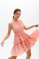 Vestido corto color salmón, con escote halter con volados y falda escalonada con volados.