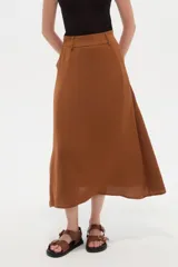 Pollera larga color marrón, con diseño fluido, pretina con trabillas y bolsillos laterales.