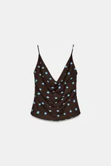 Top de tirantes finos con escote drapeado y diseño fluido. Presenta un estampado de lunares celestes sobre fondo marrón.
