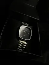 Reloj Casio Quartz con caja cuadrada plateada, esfera negra y correa de acero inoxidable plateada. Incluye fechador.