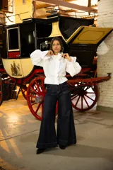 Camisa de lino color negro con cuello alto, volados frontales y mangas largas abullonadas con puños elásticos. Presenta cierre frontal con botones ocultos.