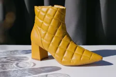 Bota corta de cuero color mostaza con diseño capitoneado, taco cuadrado y cierre lateral.