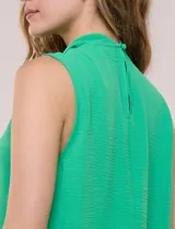 Blusa sin mangas color verde, confeccionada en crepé texturizado, con cuello alto drapeado y torsión central frontal.