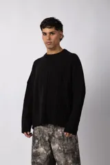 Sweater de punto color blanco con diseño de textura combinada, presentando un lado liso y otro con tejido trenzado. Posee cuello redondo, mangas largas y un corte relajado.