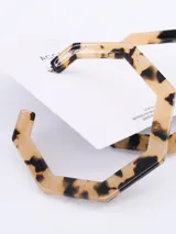 Par de aros colgantes con forma geométrica irregular, con estampado carey en tonos beige y negro.