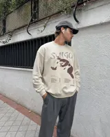 Buzo de cuello redondo color beige, con diseño gráfico en el frente que incluye la leyenda 'Sumo', una ilustración de un luchador de sumo y listado de canciones.