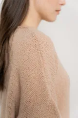 Sweater de punto con textura suave, color beige, de corte holgado y mangas largas con terminación de cuello y puños en estilo rulé.