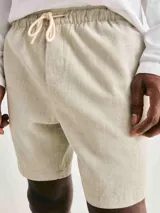 Bermuda de corte recto confeccionada en tela texturizada, con cintura elástica y cordón ajustable. Cuenta con bolsillos laterales y un diseño minimalista.